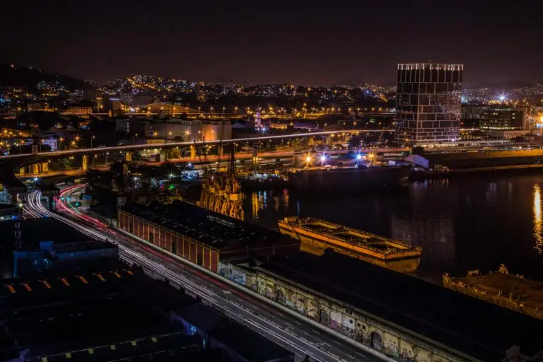 Night scene of Rio de Janeiro featuring illuminated cityscape, highways, harbour, and light trails.
